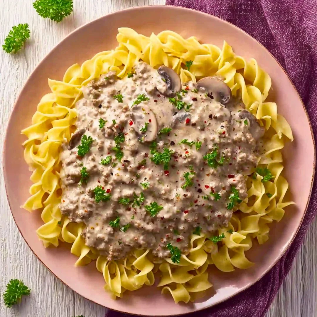 Crockpot ground turkey stroganoff served in a bowl with noodles and herbs