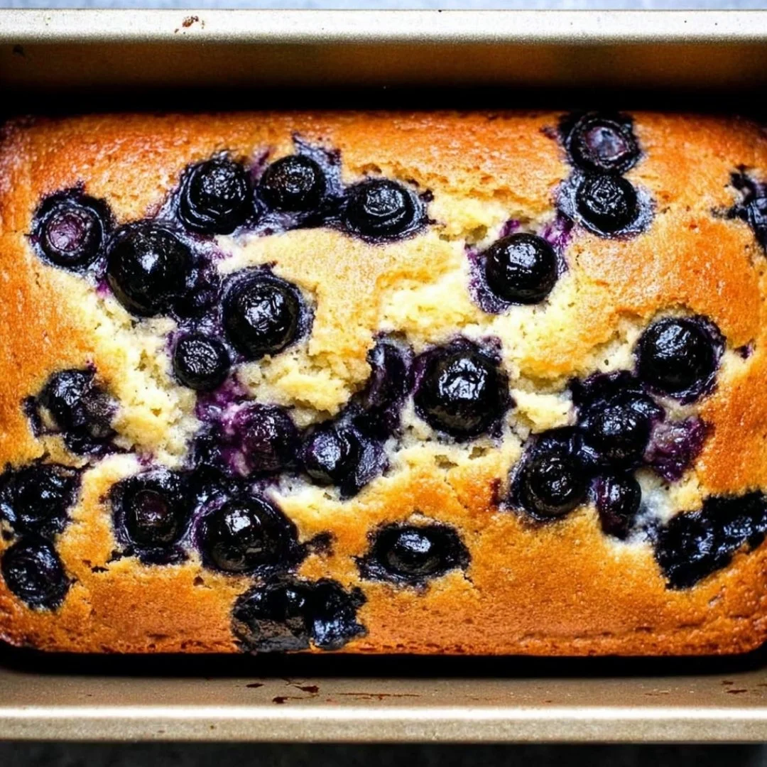 Slice of easy lemon blueberry bread with lemon glaze on a plate.