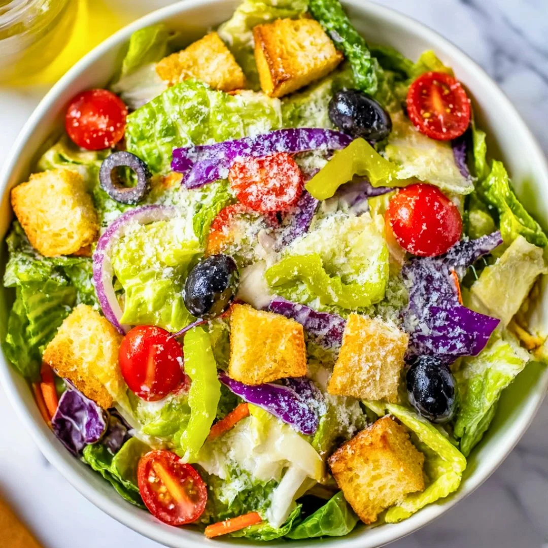 A fresh and vibrant Olive Garden Salad served with crisp vegetables and dressing.