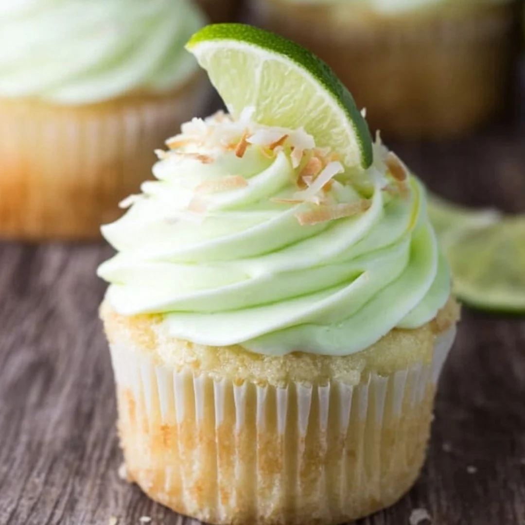 Delicious coconut cupcakes with fresh lime frosting on a pastel background.